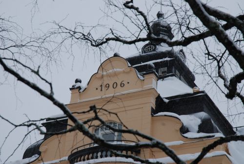 Statt fasad vinter torn med kala björkgrenar framför
